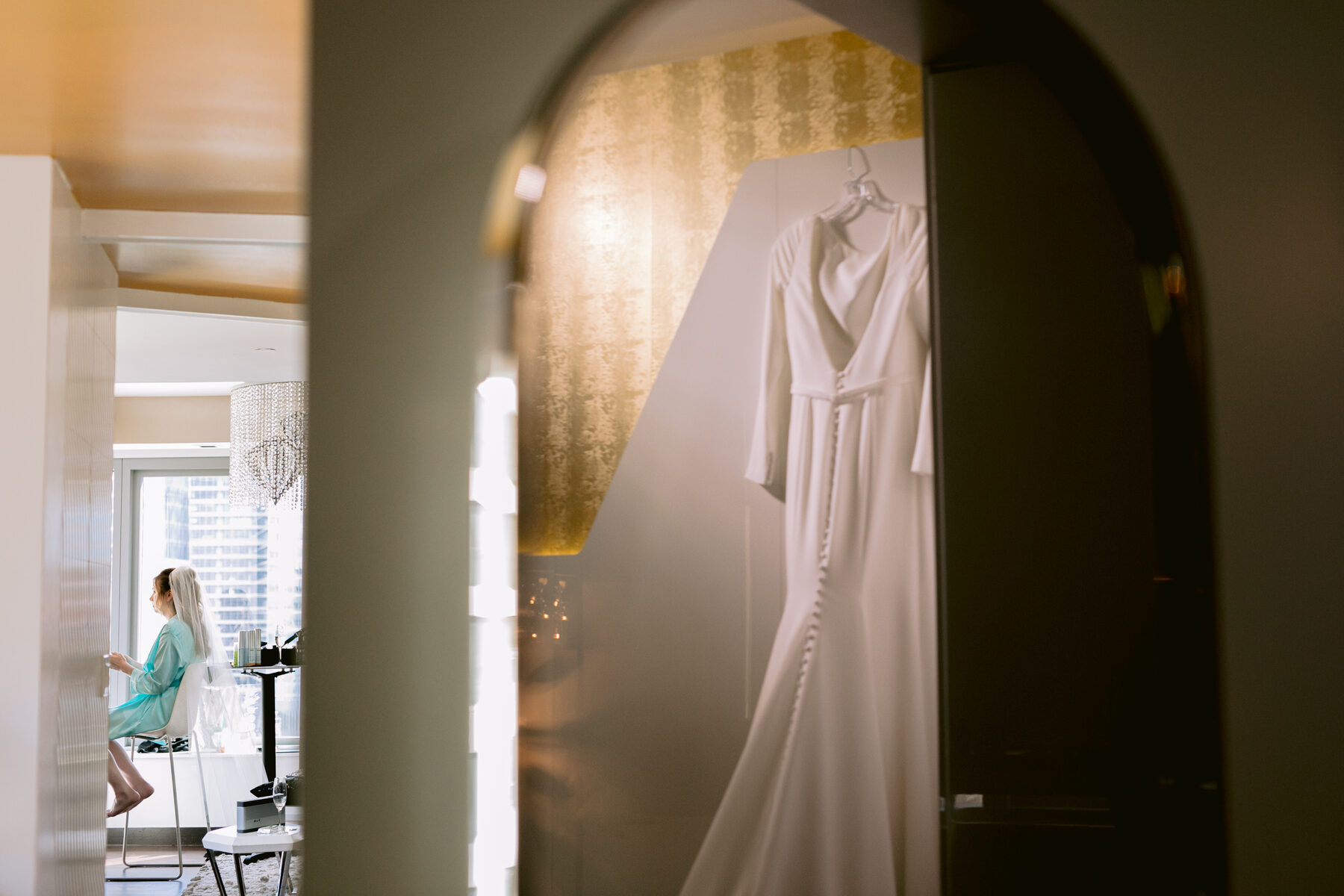 Wedding gown detail hanging in a sunlit doorway